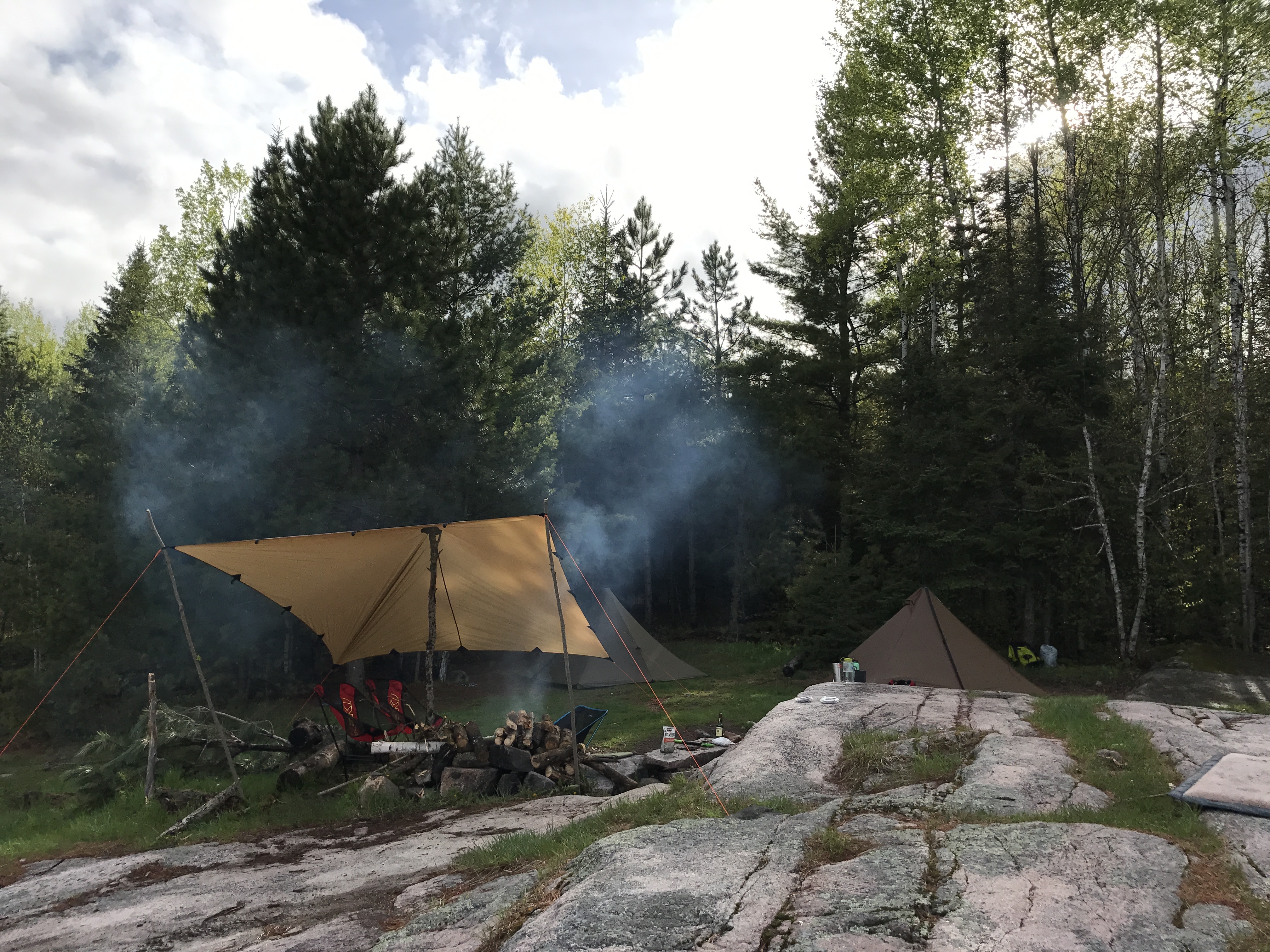 Dst Tarp as a rain shelter near a cmapfire in a clearing in the forrest