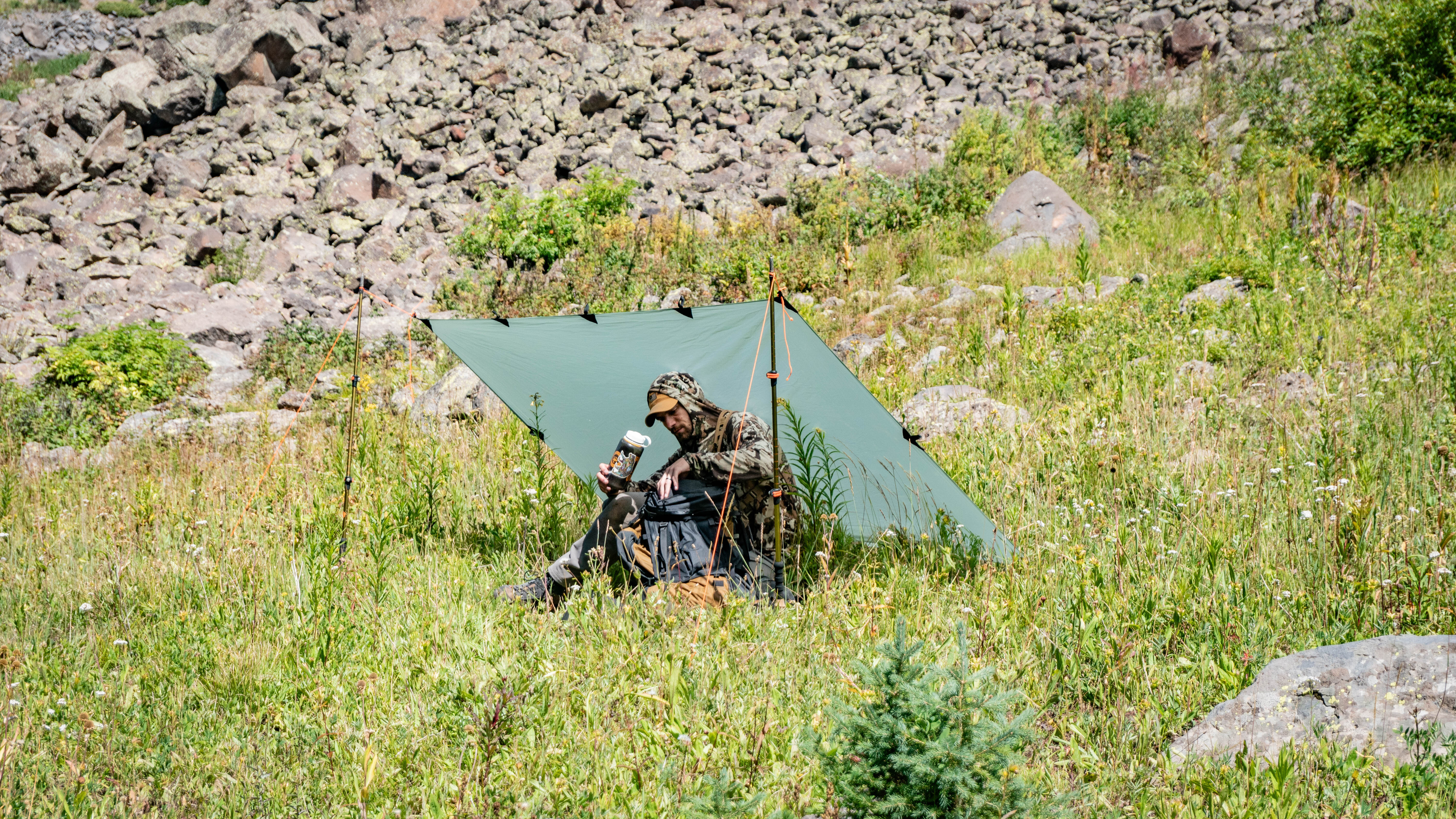 Gunnison Tarp being used as a shelter to block the wind in an alpine meadow